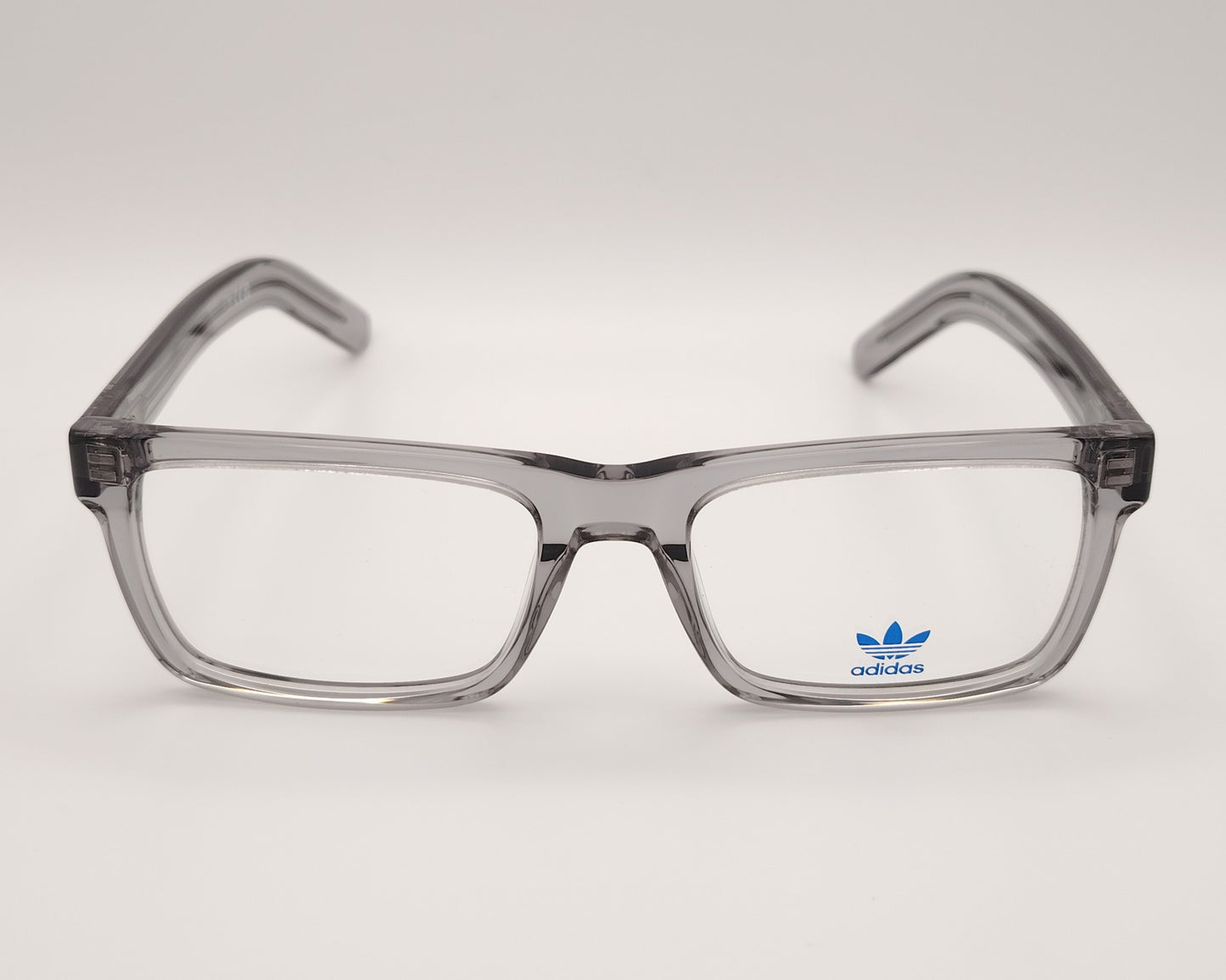 adidas or5107 020 gafas de vista con montura rectangular en acetato transparente gris diseño moderno con varillas decoradas con líneas en relieve y el icónico logo trefoil en metal estructura ligera y versátil