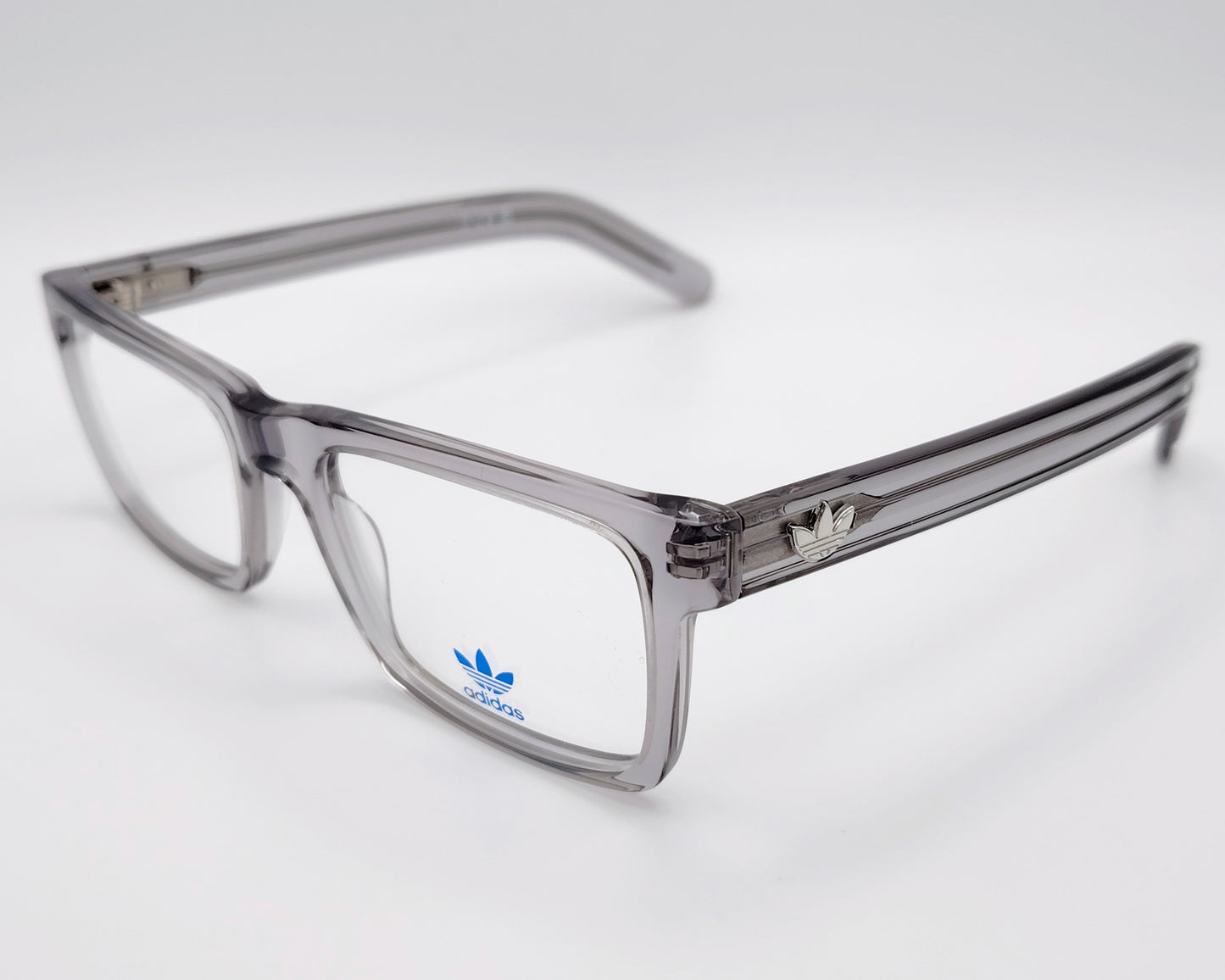 adidas or5107 020 gafas de vista con montura rectangular en acetato transparente gris diseño moderno con varillas decoradas con líneas en relieve y el icónico logo trefoil en metal estructura ligera y versátil