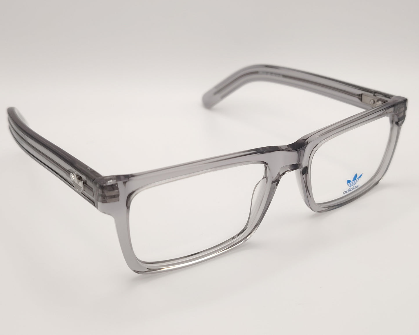 adidas or5107 020 gafas de vista con montura rectangular en acetato transparente gris diseño moderno con varillas decoradas con líneas en relieve y el icónico logo trefoil en metal estructura ligera y versátil