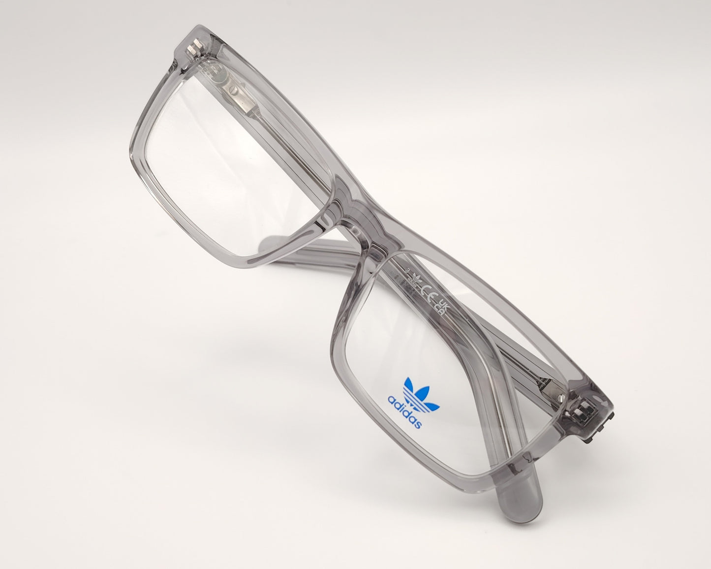 Aadidas or5107 020 gafas de vista con montura rectangular en acetato transparente gris diseño moderno con varillas decoradas con líneas en relieve y el icónico logo trefoil en metal estructura ligera y versátil