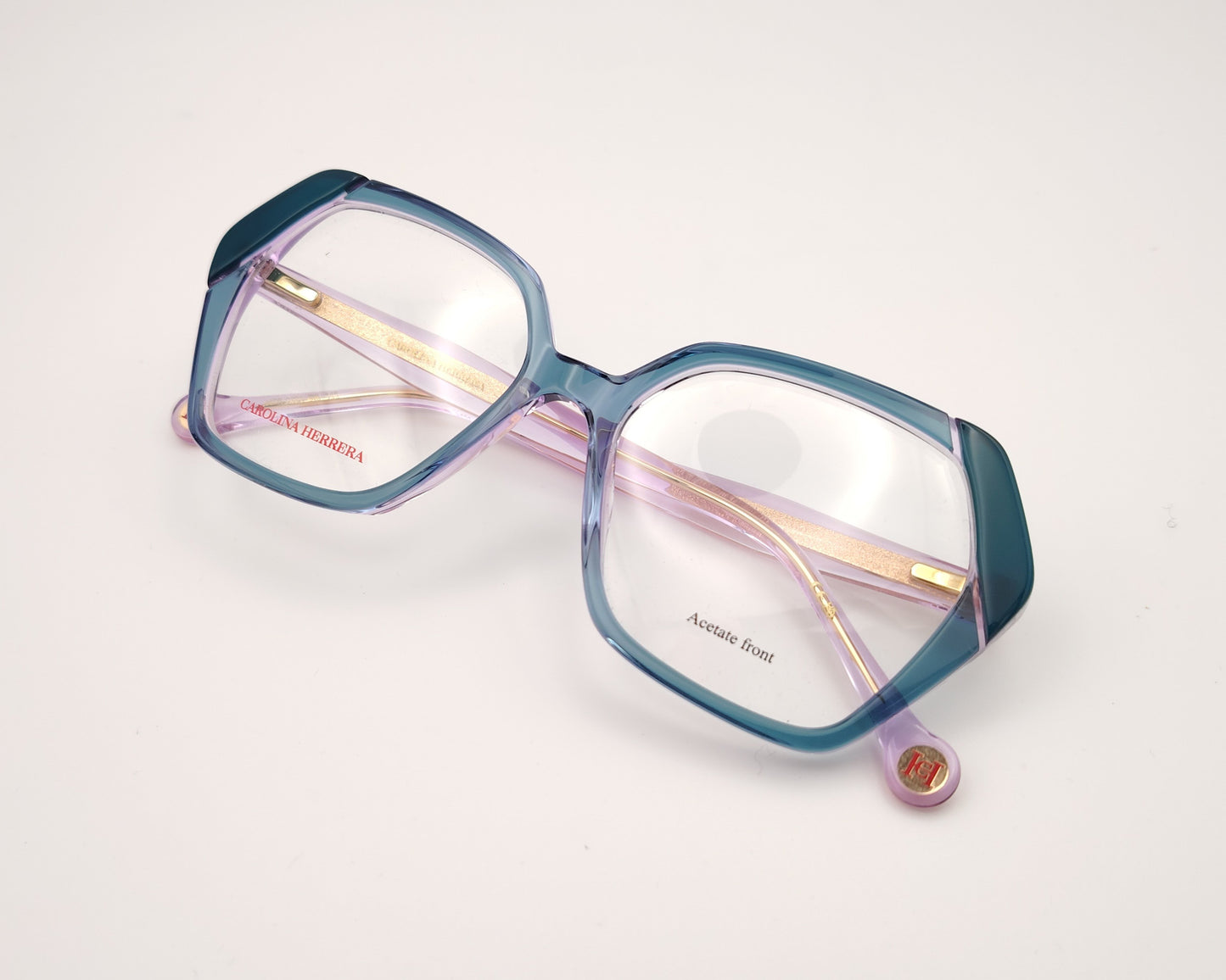 gafas graduadas con montura geométrica en tonos morado y verde agua, varillas rosadas y logo dorado de carolina herrera