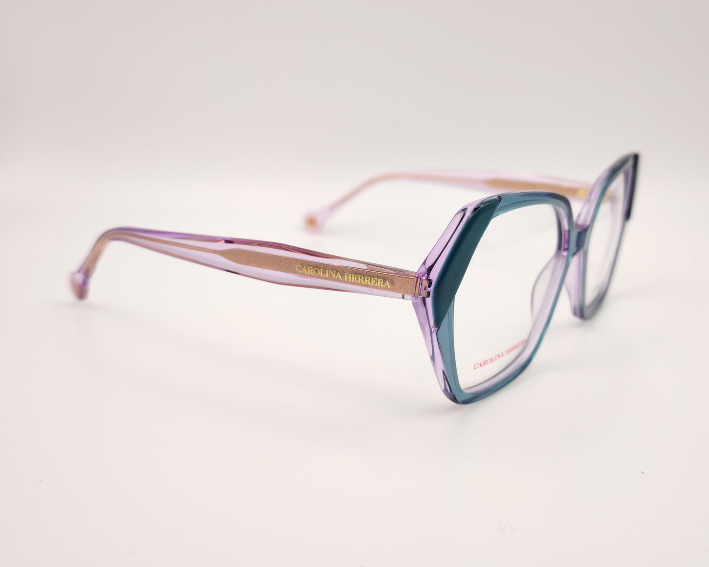 gafas graduadas con montura geométrica en tonos morado y verde agua, varillas rosadas y logo dorado de carolina herrera