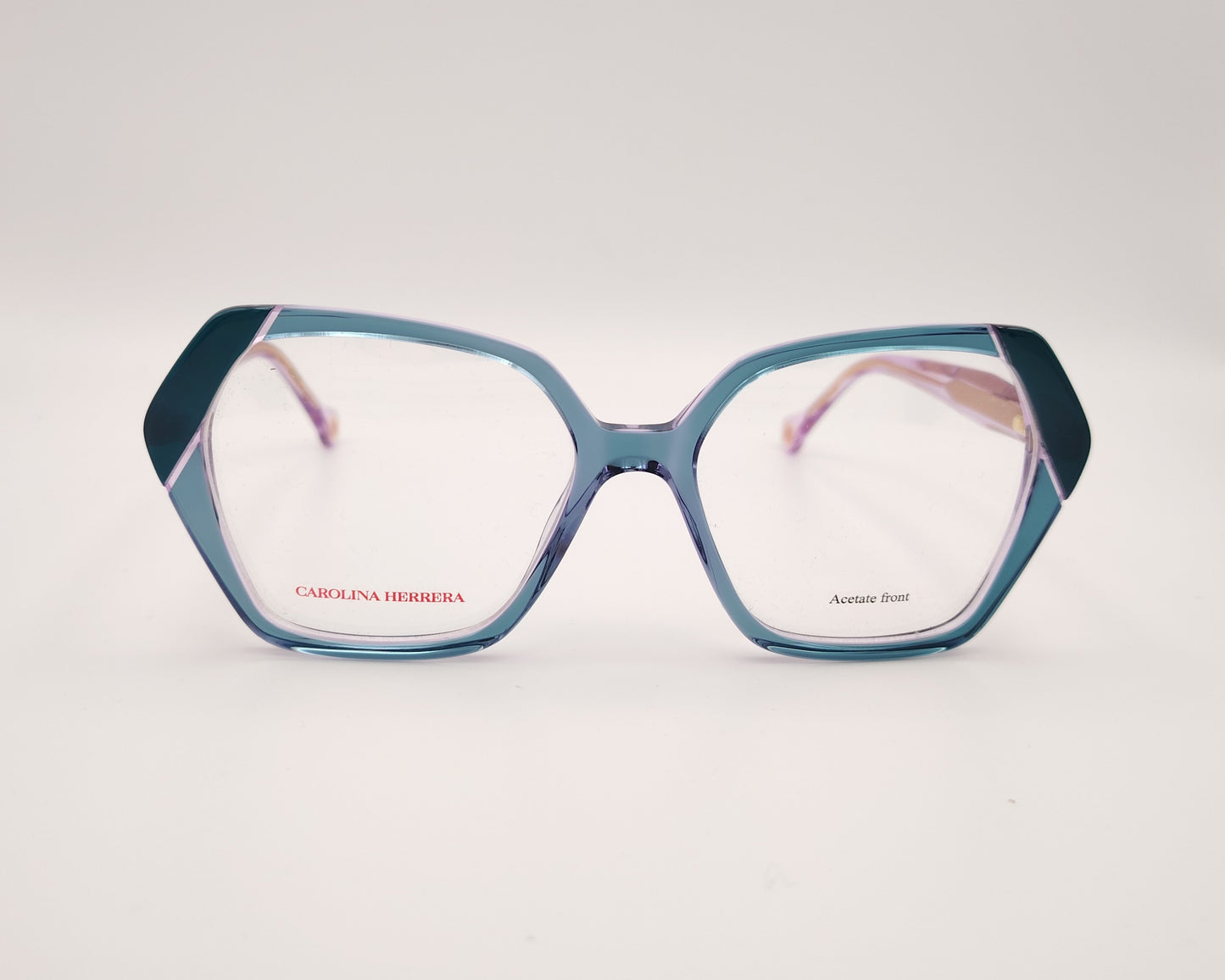gafas graduadas con montura geométrica en tonos morado y verde agua, varillas rosadas y logo dorado de carolina herrera