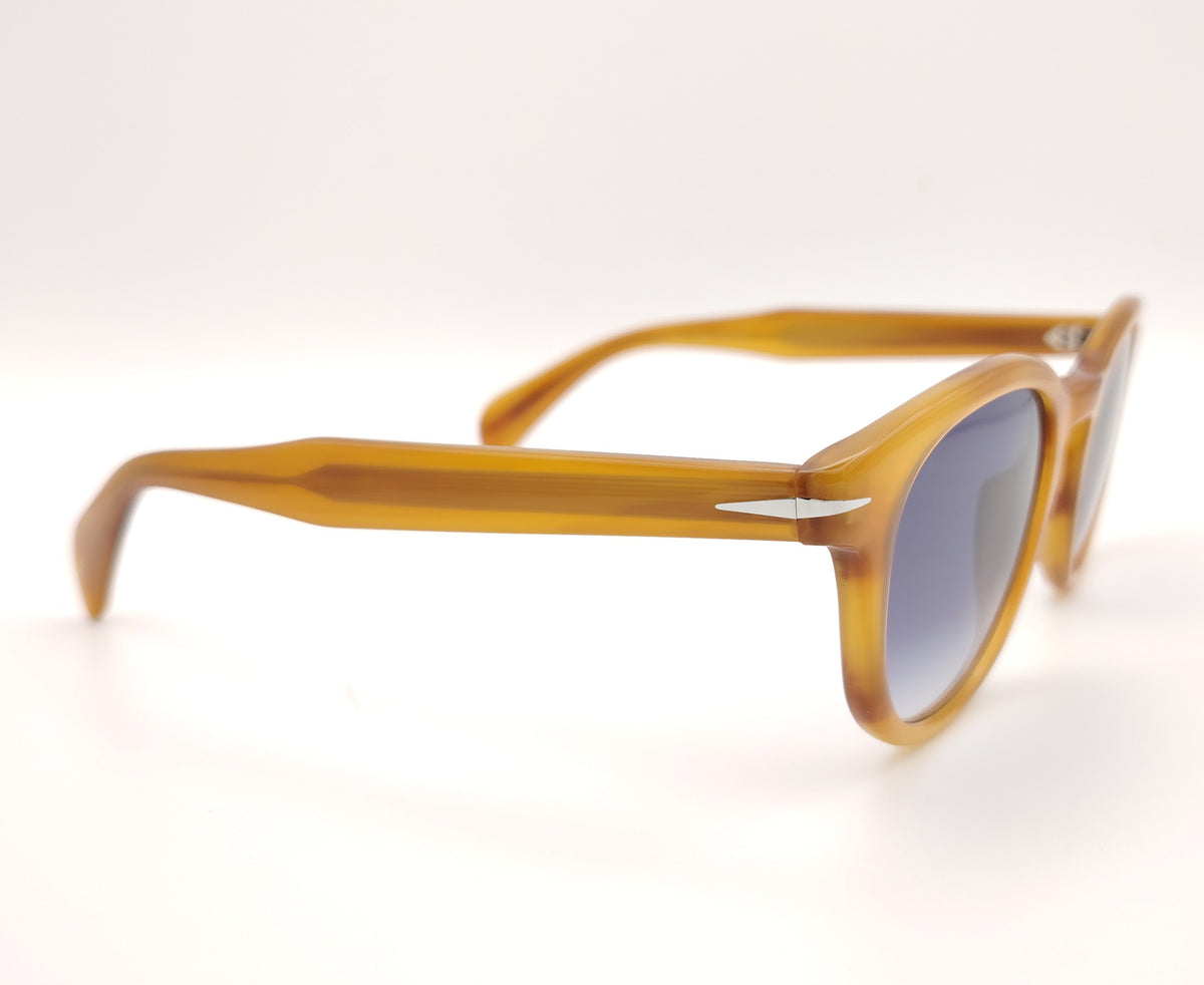 gafas de sol con montura translúcida color miel y lentes degradadas azules de forma redondeada