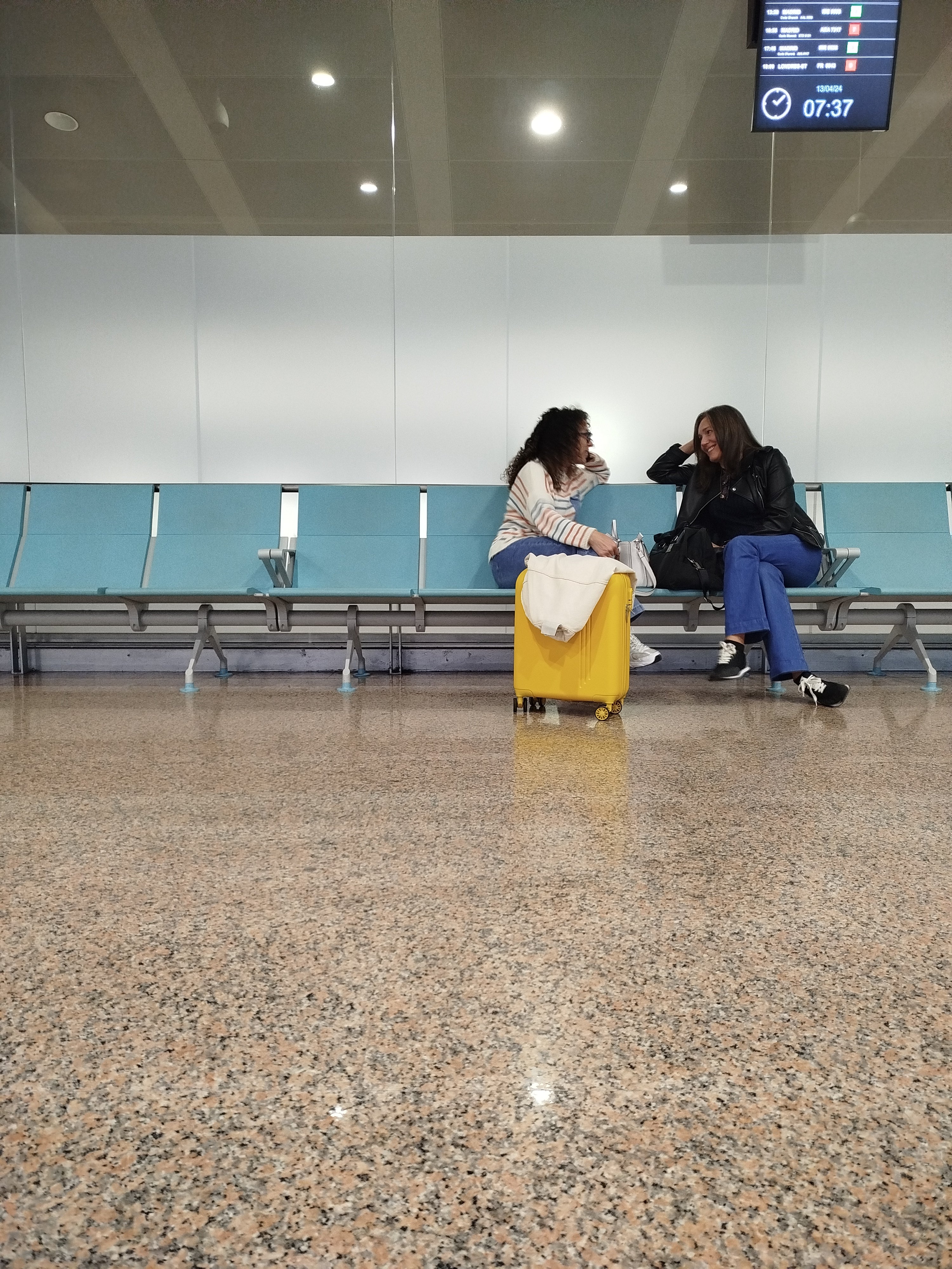 dos mujeres conversando mientras esperan para coger su vuelo en un aeropuerto