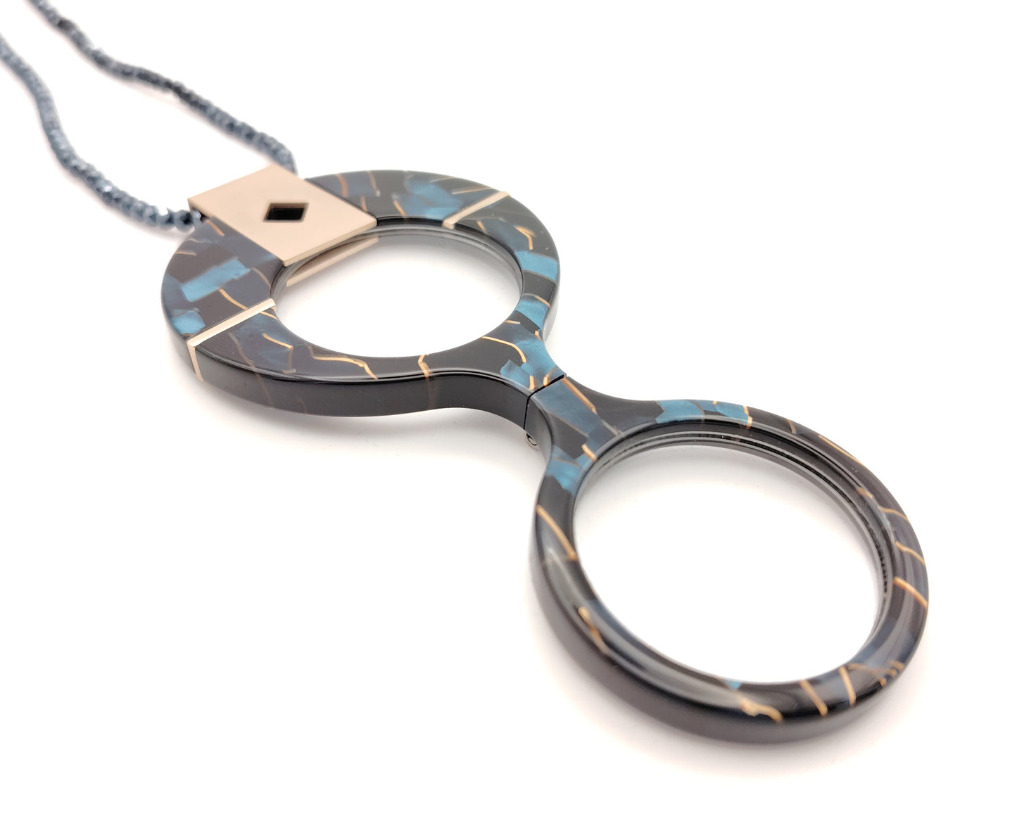 lente de lectura plegable con diseño negro azul y dorado colgado de cadena de cuentas