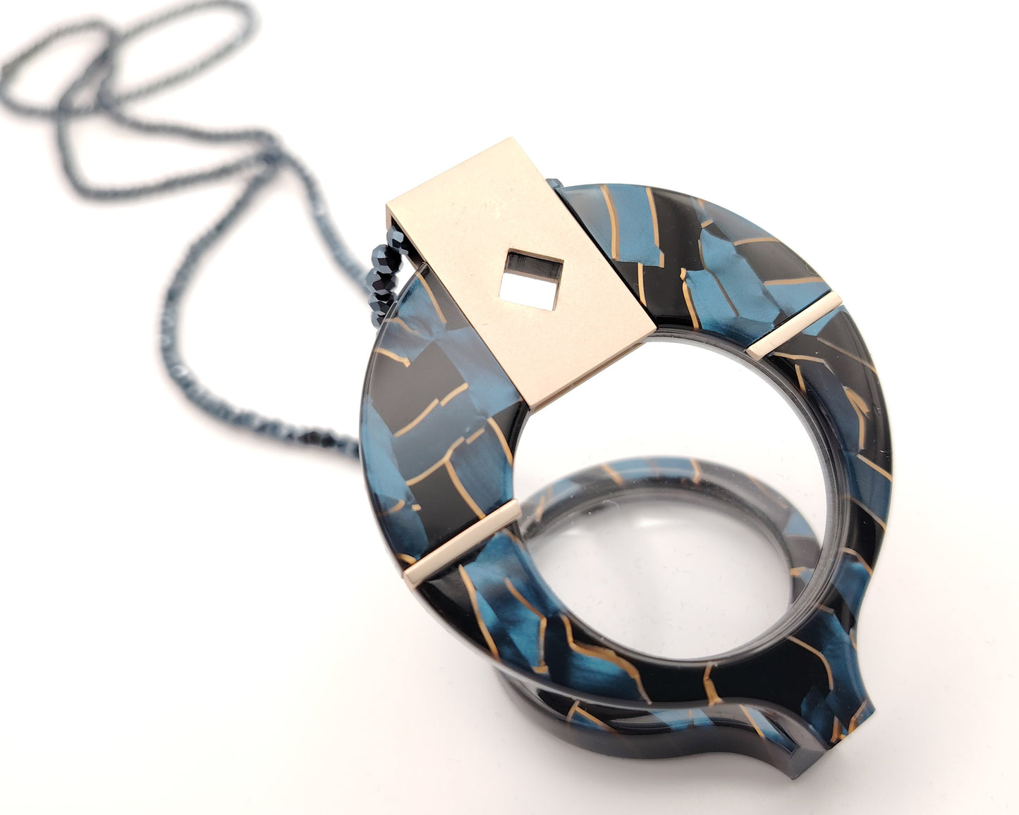 lente de lectura plegable con diseño negro azul y dorado colgado de cadena de cuentas
