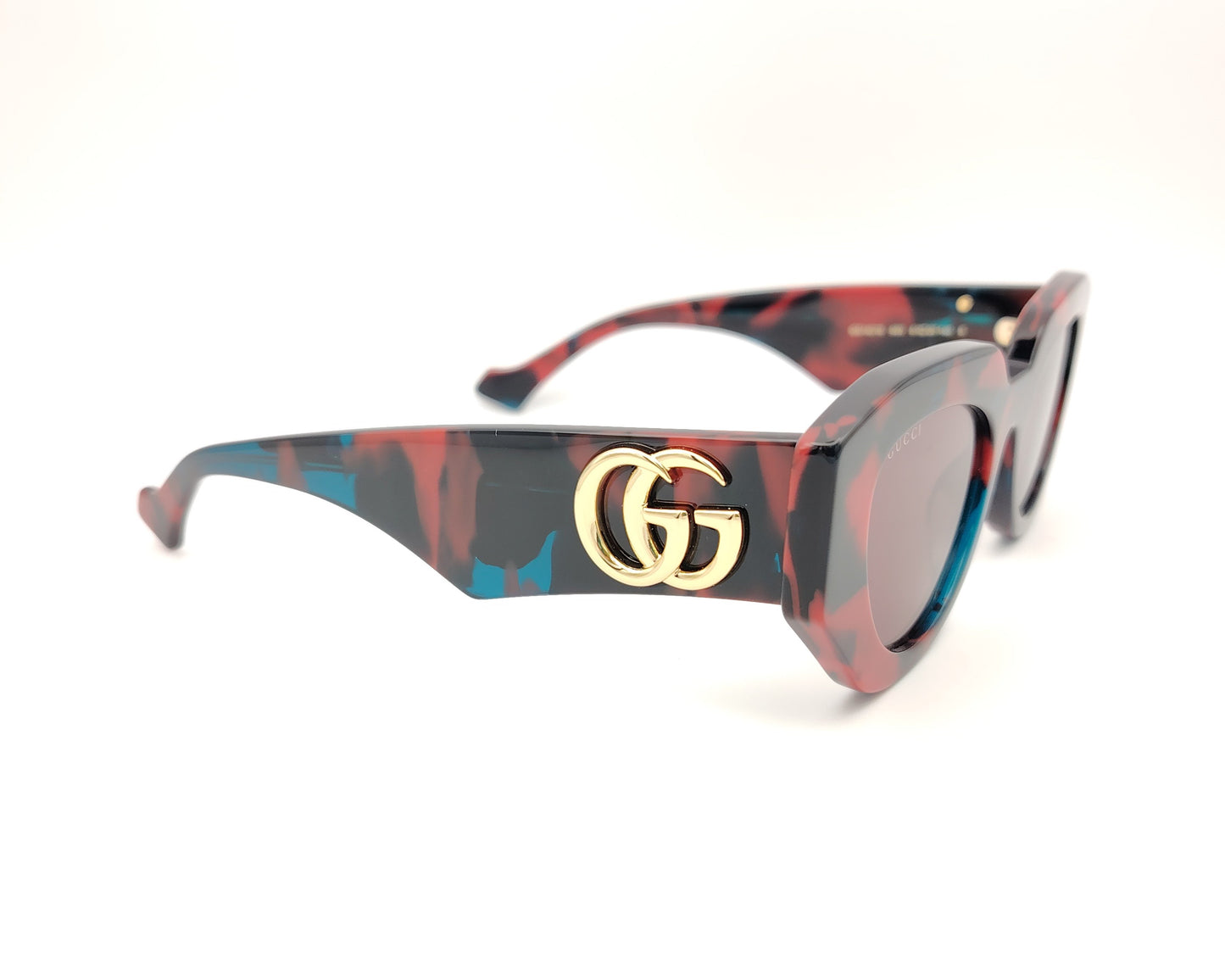 gafas de sol gucci con montura geométrica marmolada en rojo azul y negro y lentes rosadas