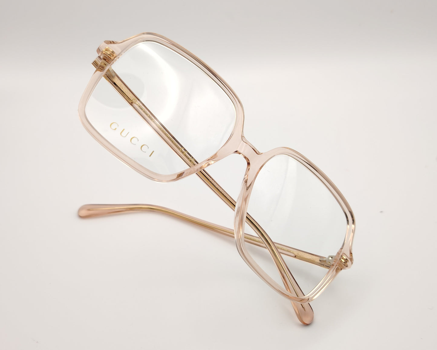 gafas graduadas de oversize con montura cuadrada en tono rosa claro translúcido y logotipo gucci en la lente izquierda