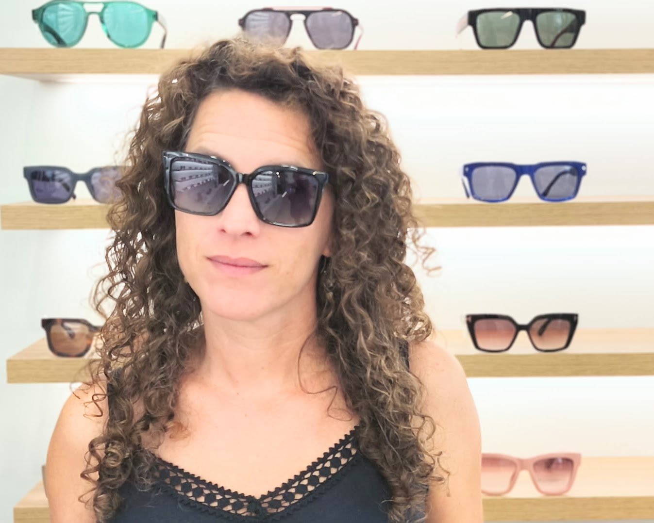 gafas de sol negras con montura en forma cuadrada, cristales degradados en tonos azulados y detalles dorados con símbolos decorativos en la varilla