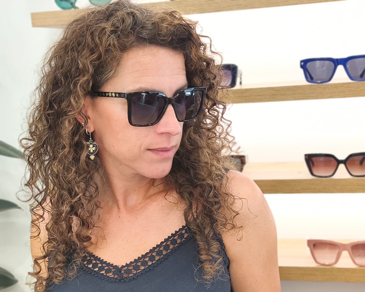 gafas de sol negras con montura en forma cuadrada, cristales degradados en tonos azulados y detalles dorados con símbolos decorativos en la varilla