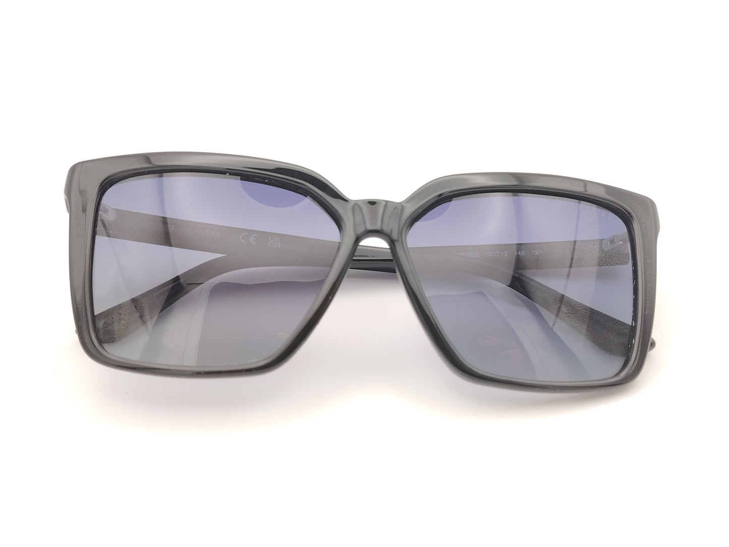 gafas de sol negras con montura en forma cuadrada, cristales degradados en tonos azulados y detalles dorados con símbolos decorativos en la varilla