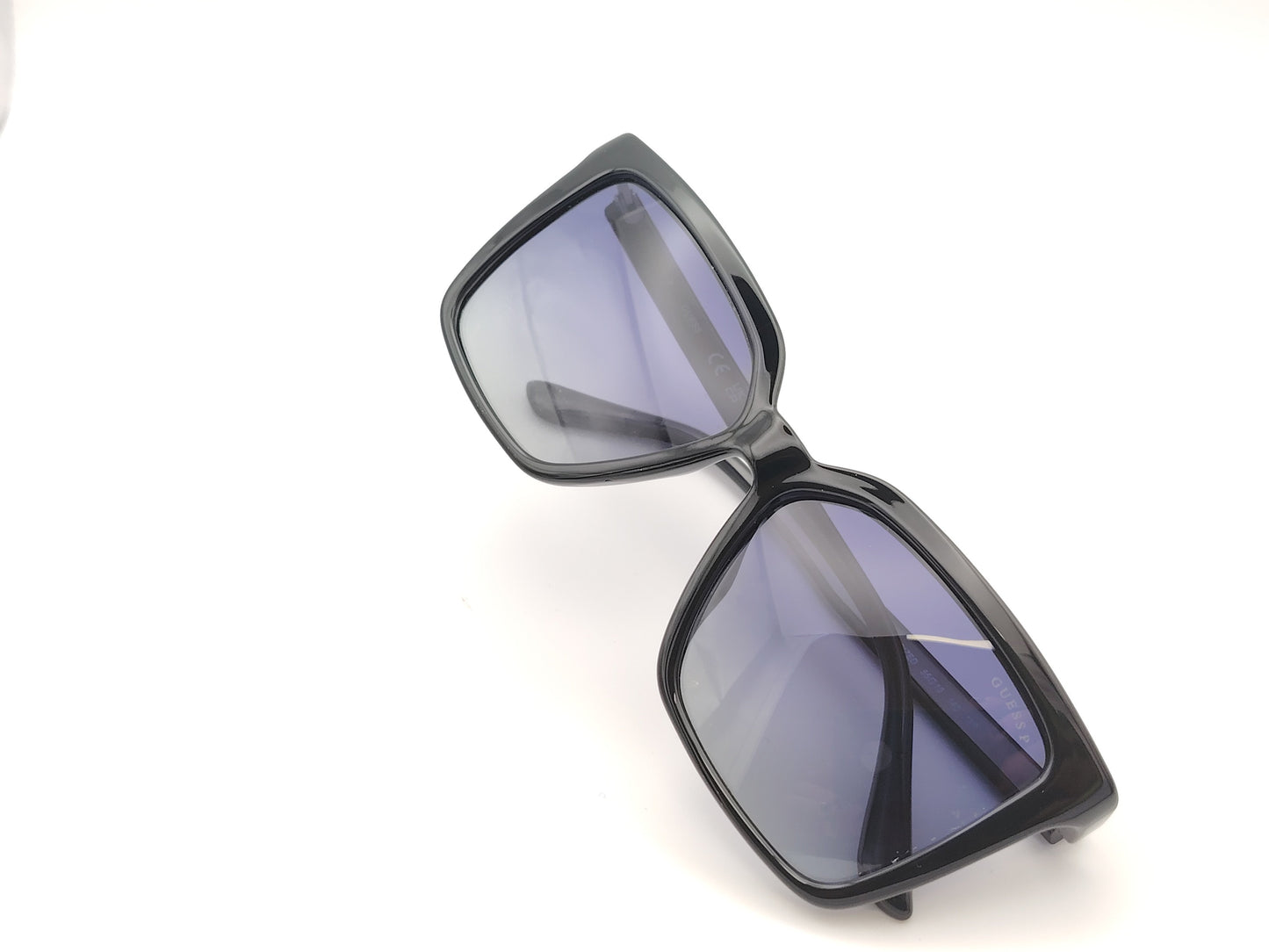 gafas de sol negras con montura en forma cuadrada, cristales degradados en tonos azulados y detalles dorados con símbolos decorativos en la varilla