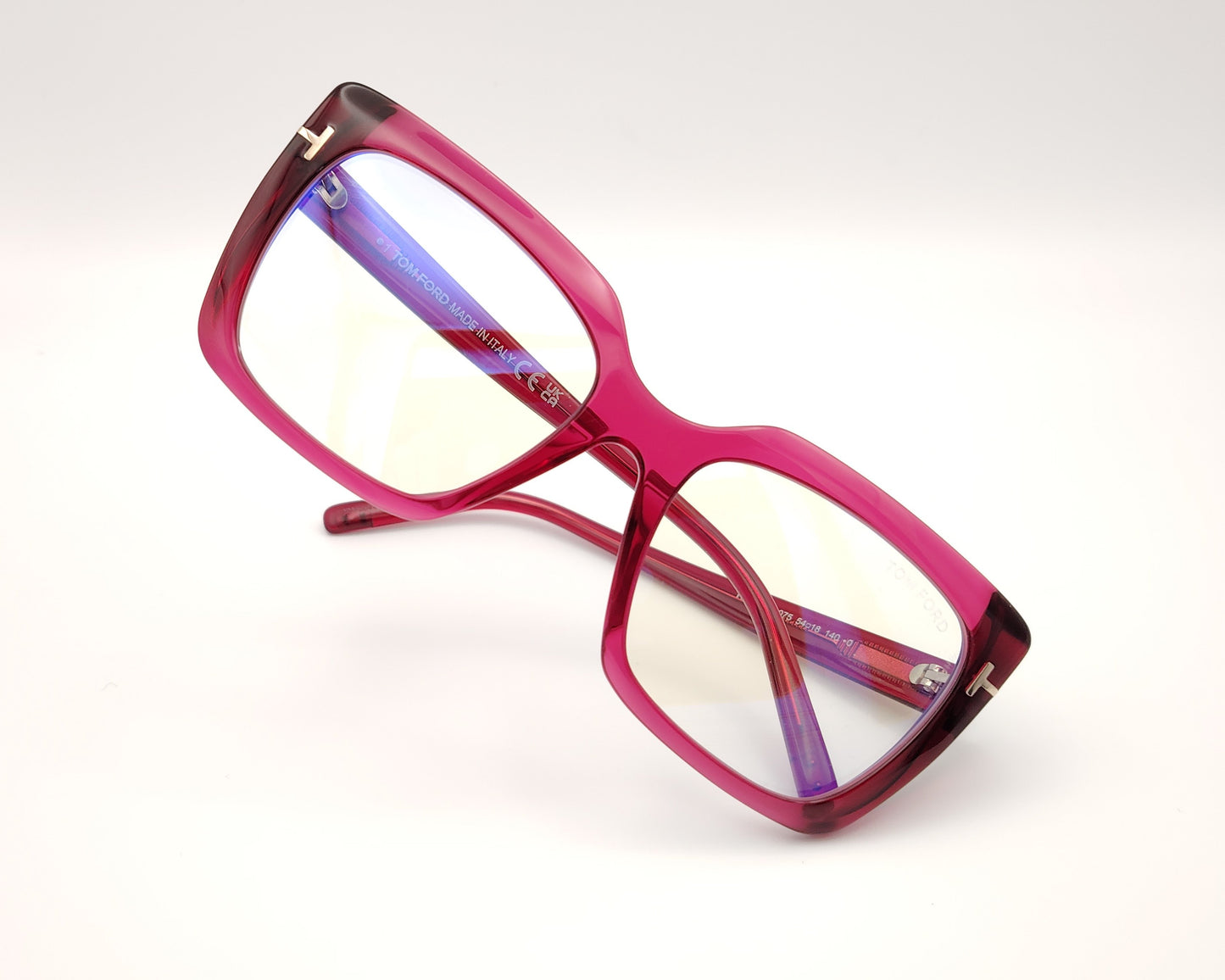 gafas graduadas con montura rectangular en acetato fucsia translúcido y detalle metálico dorado en forma de t en las varillas