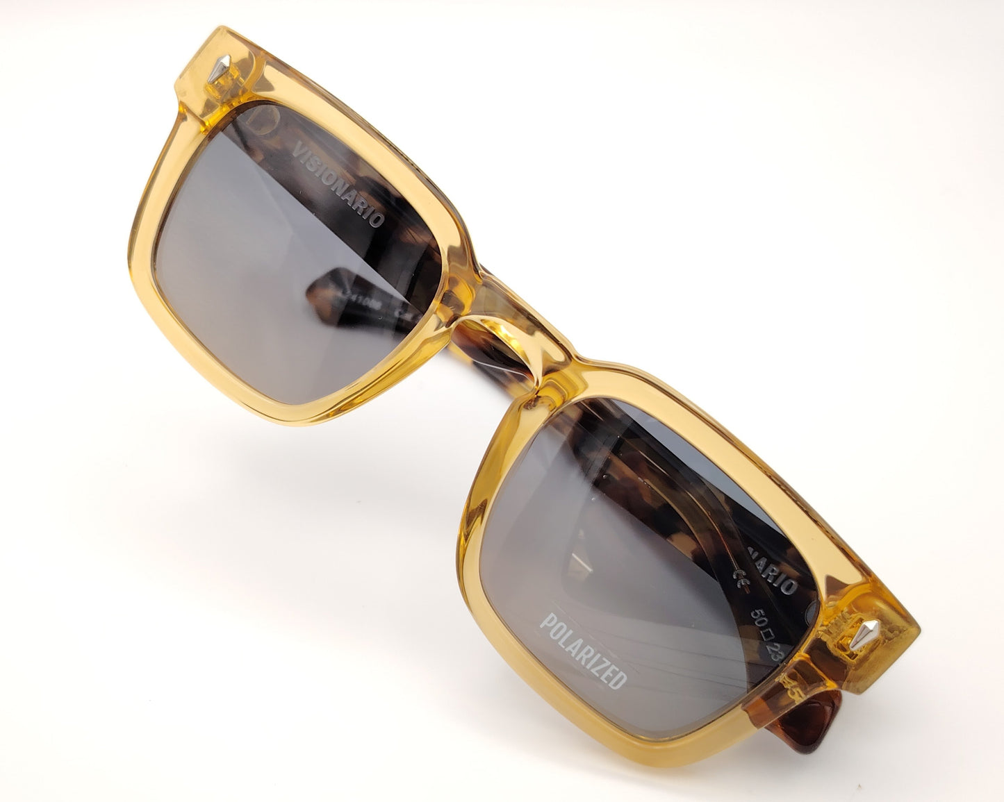 gafas de sol visionario linch 03 con montura cuadrada en color ámbar translúcido, lentes polarizadas en tono gris y detalles metálicos en las esquinas