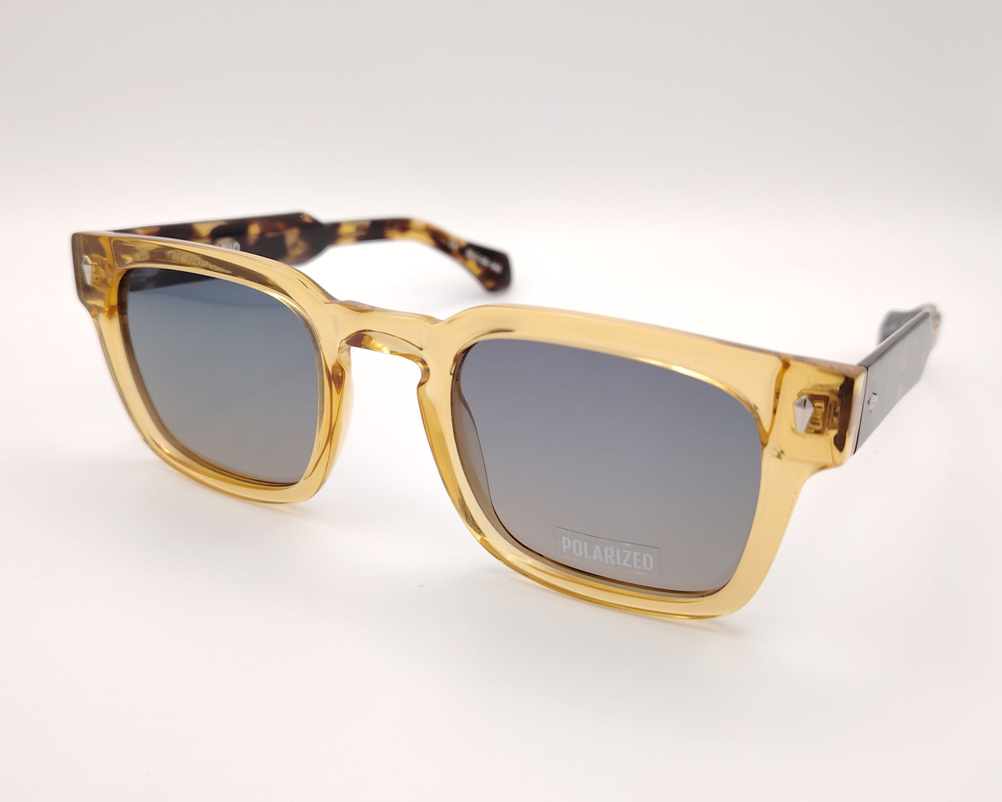 gafas de sol visionario linch 03 con montura cuadrada en color ámbar translúcido, lentes polarizadas en tono gris y detalles metálicos en las esquinas