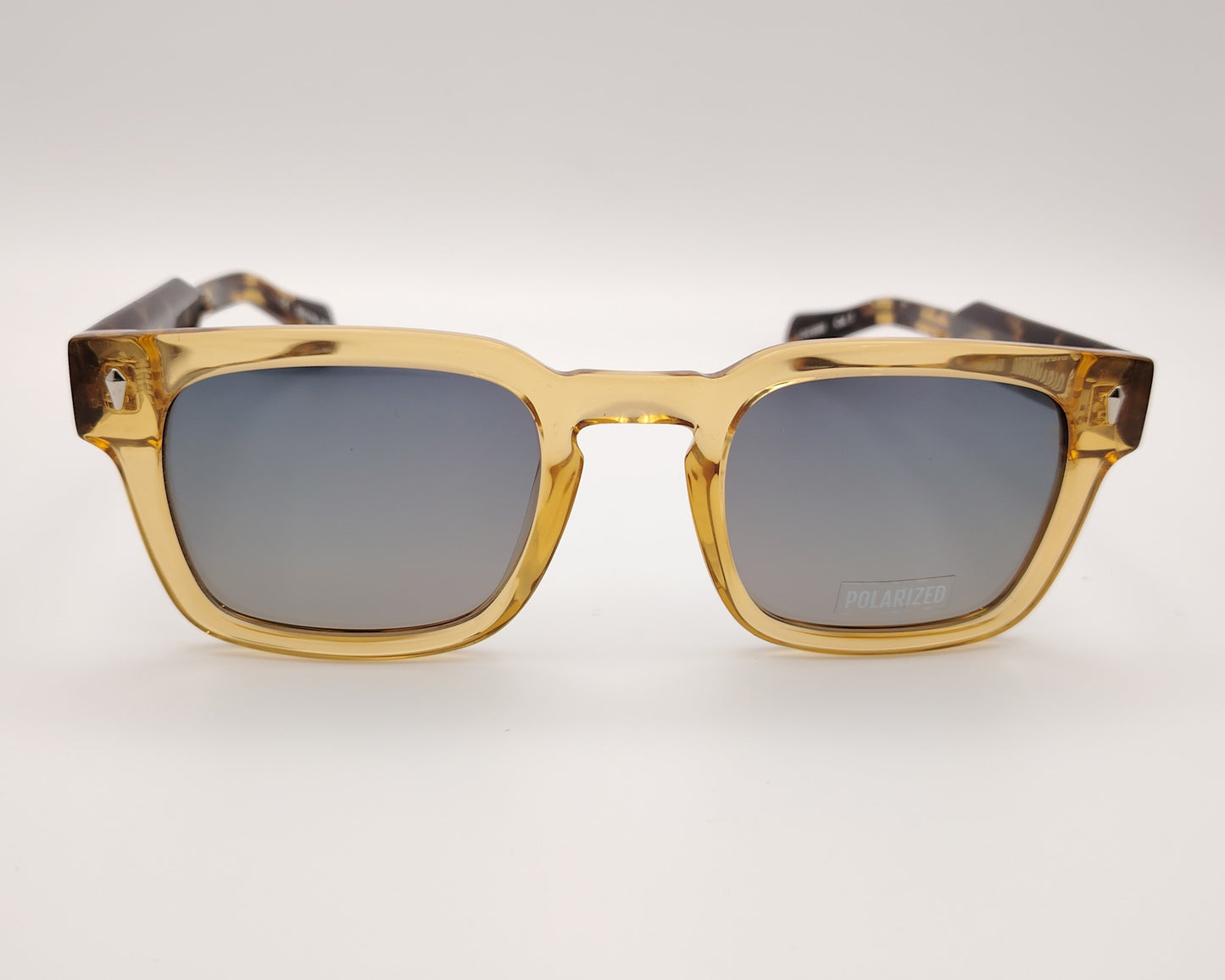 gafas de sol visionario linch 03 con montura cuadrada en color ámbar translúcido, lentes polarizadas en tono gris y detalles metálicos en las esquinas