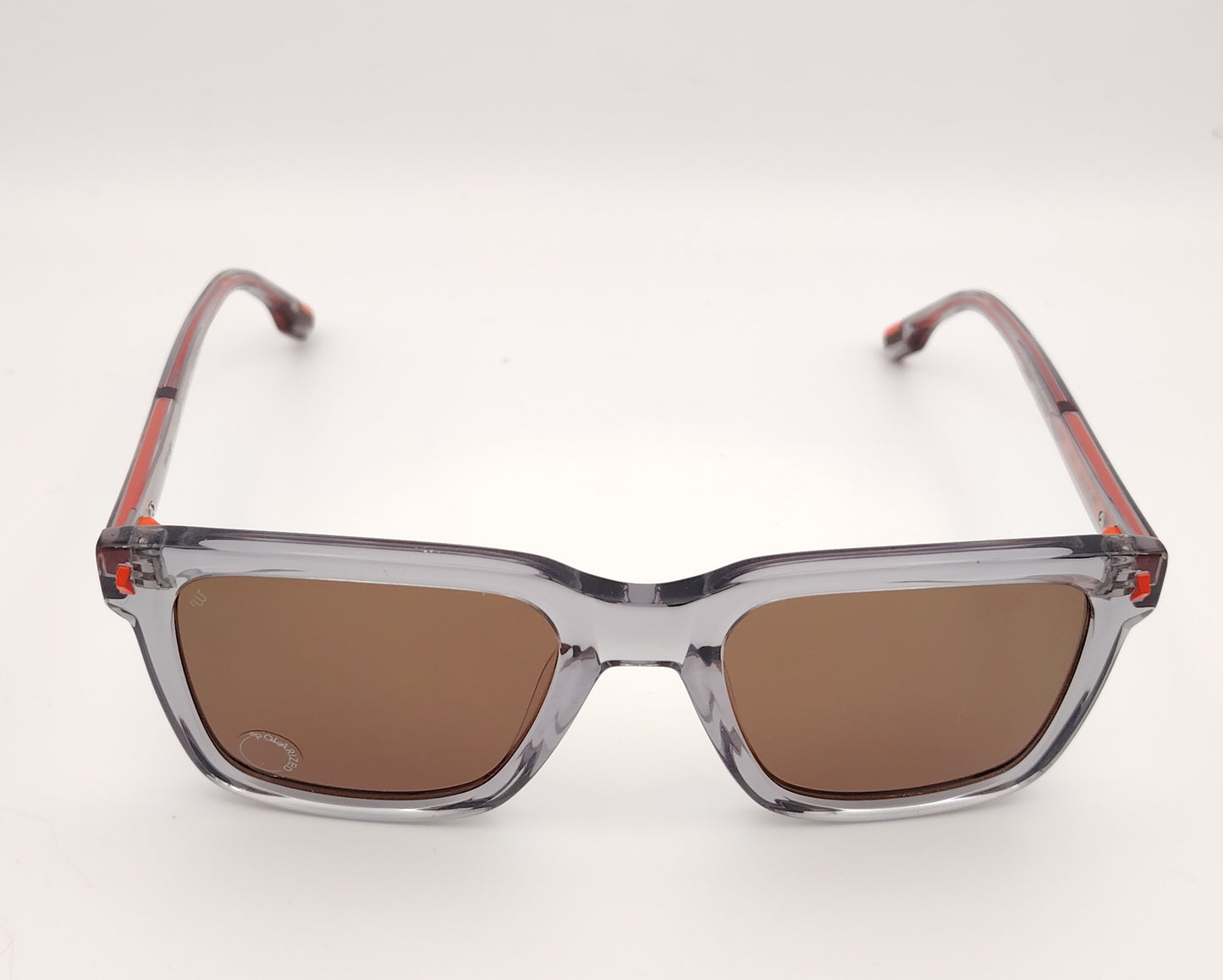 woodys burke 03 gafas de sol de forma rectangular con montura gris translúcida y detalles en naranja en las varillas y cristales polarizados marrones, diseño moderno ideal para un estilo urbano y actual