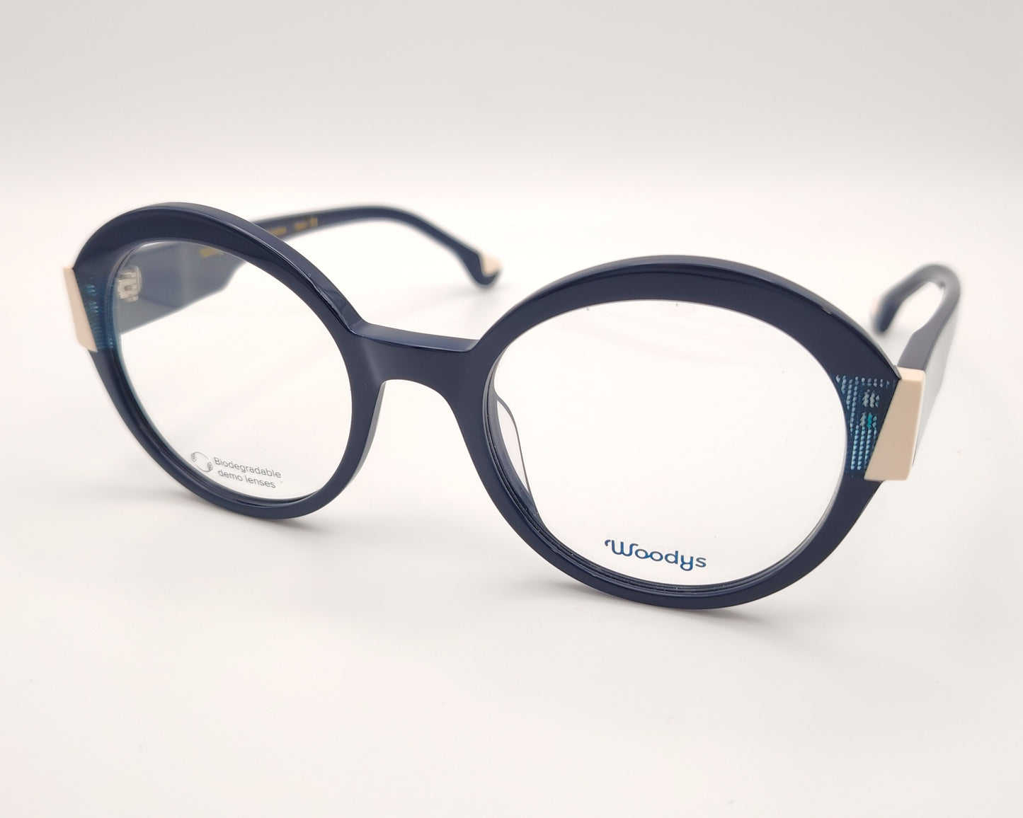 gafas graduadas woodys kilda 04 con montura de acetato en color azul marino diseño redondo con detalles geométricos en crema y texturas azuladas en las esquinas varillas en el mismo tono con sutiles detalles que aportan un estilo elegante y distintivo