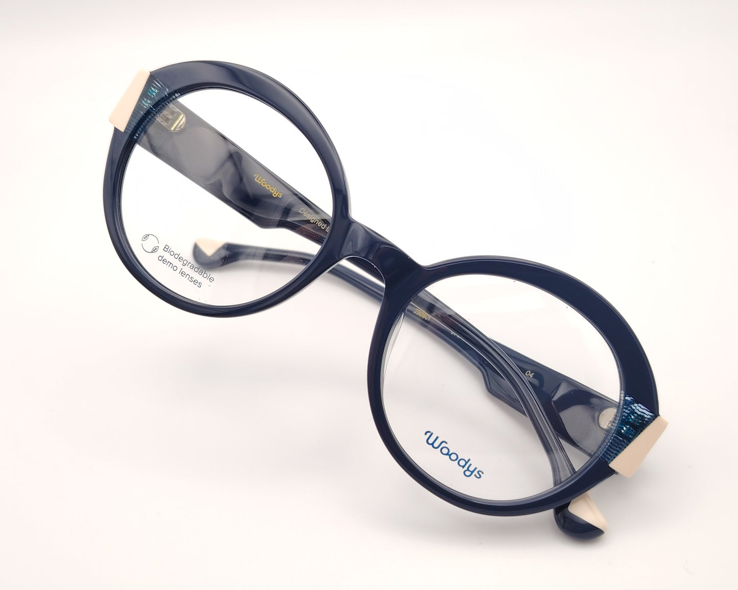 gafas graduadas woodys kilda 04 con montura de acetato en color azul marino diseño redondo con detalles geométricos en crema y texturas azuladas en las esquinas varillas en el mismo tono con sutiles detalles que aportan un estilo elegante y distintivo