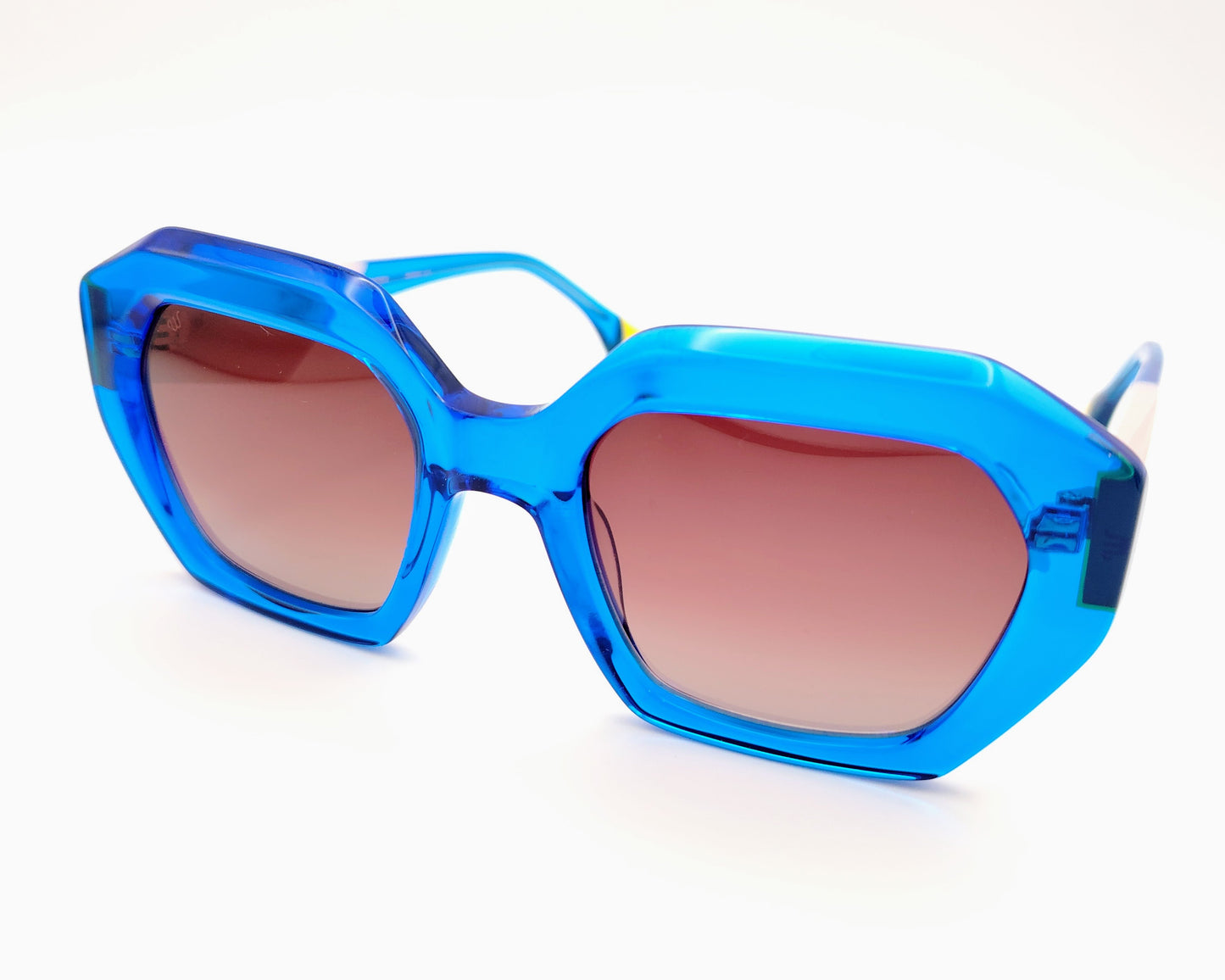 gafas de sol woodys meritxell 04 con montura oversize de acetato azul translúcido diseño geométrico con detalles en rosa y amarillo lentes degradadas en tono marrón varillas con contraste de color