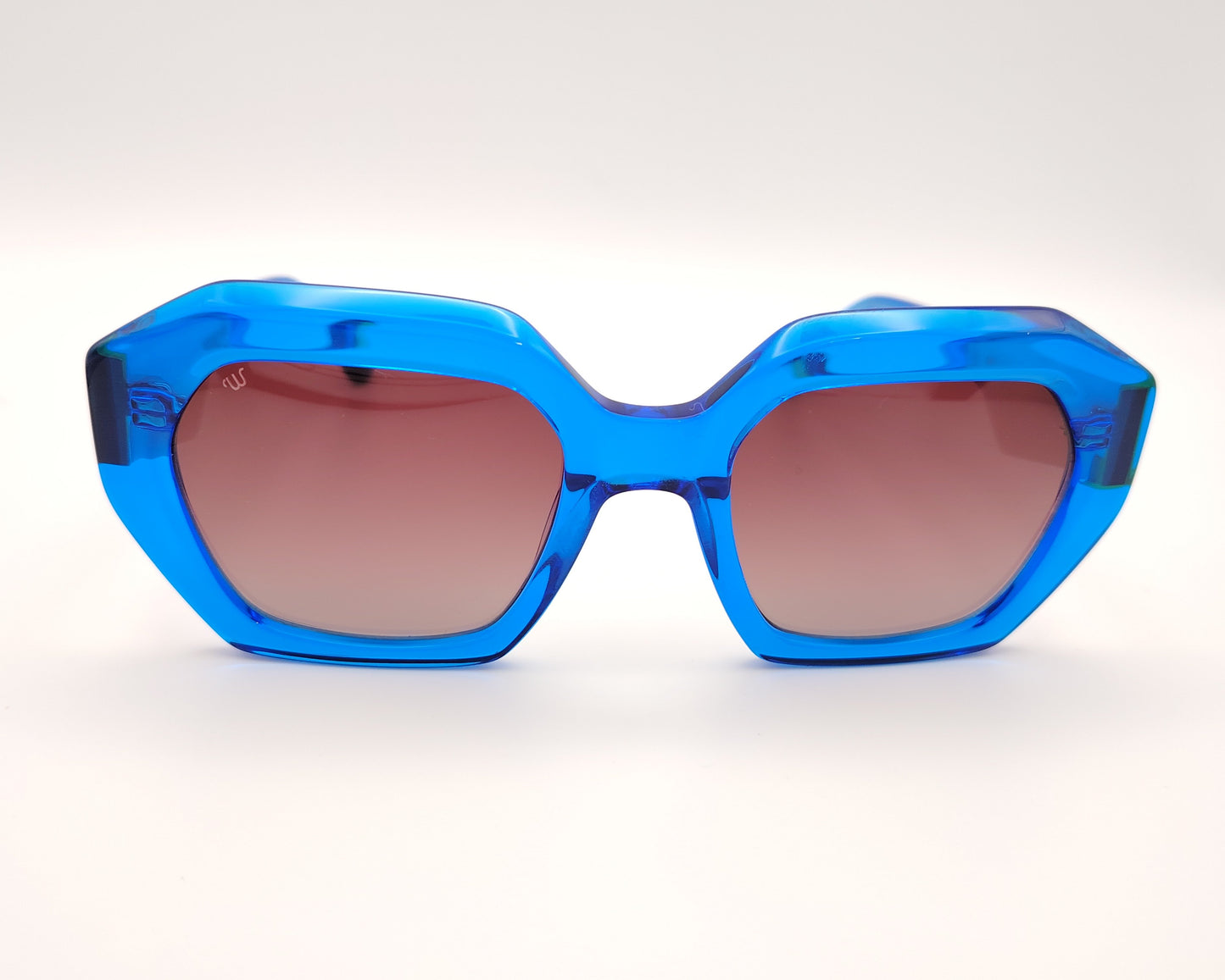 gafas de sol woodys meritxell 04 con montura oversize de acetato azul translúcido diseño geométrico con detalles en rosa y amarillo lentes degradadas en tono marrón varillas con contraste de color