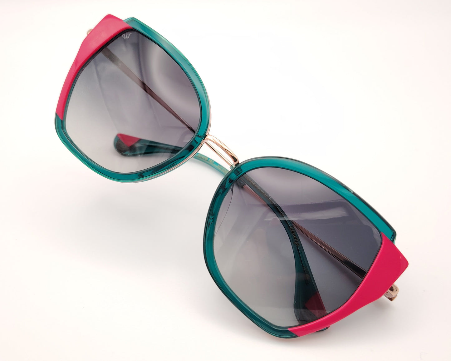 gafas de sol woodys vittoria 03 con montura geométrica con estructura en metal dorado y aro en acetato verde y detalles en rosa diseño llamativo con lentes degradadas en gris y varillas finas