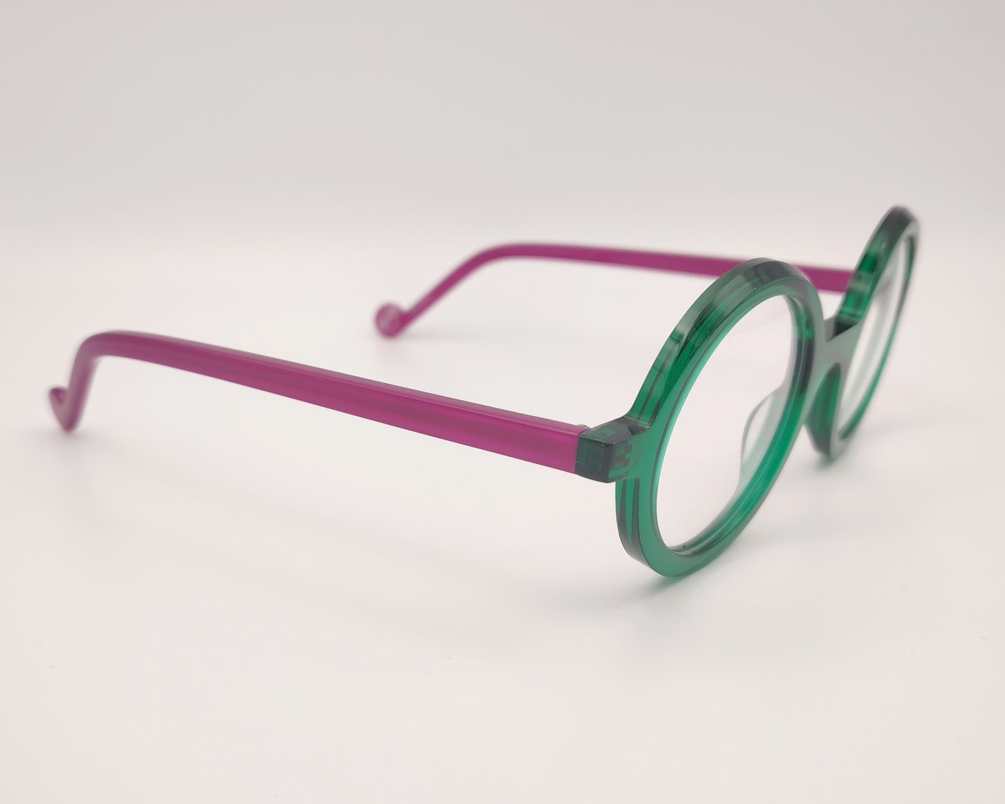 gafas redondas con frente verde esmeralda y varillas fucsia traslúcidas