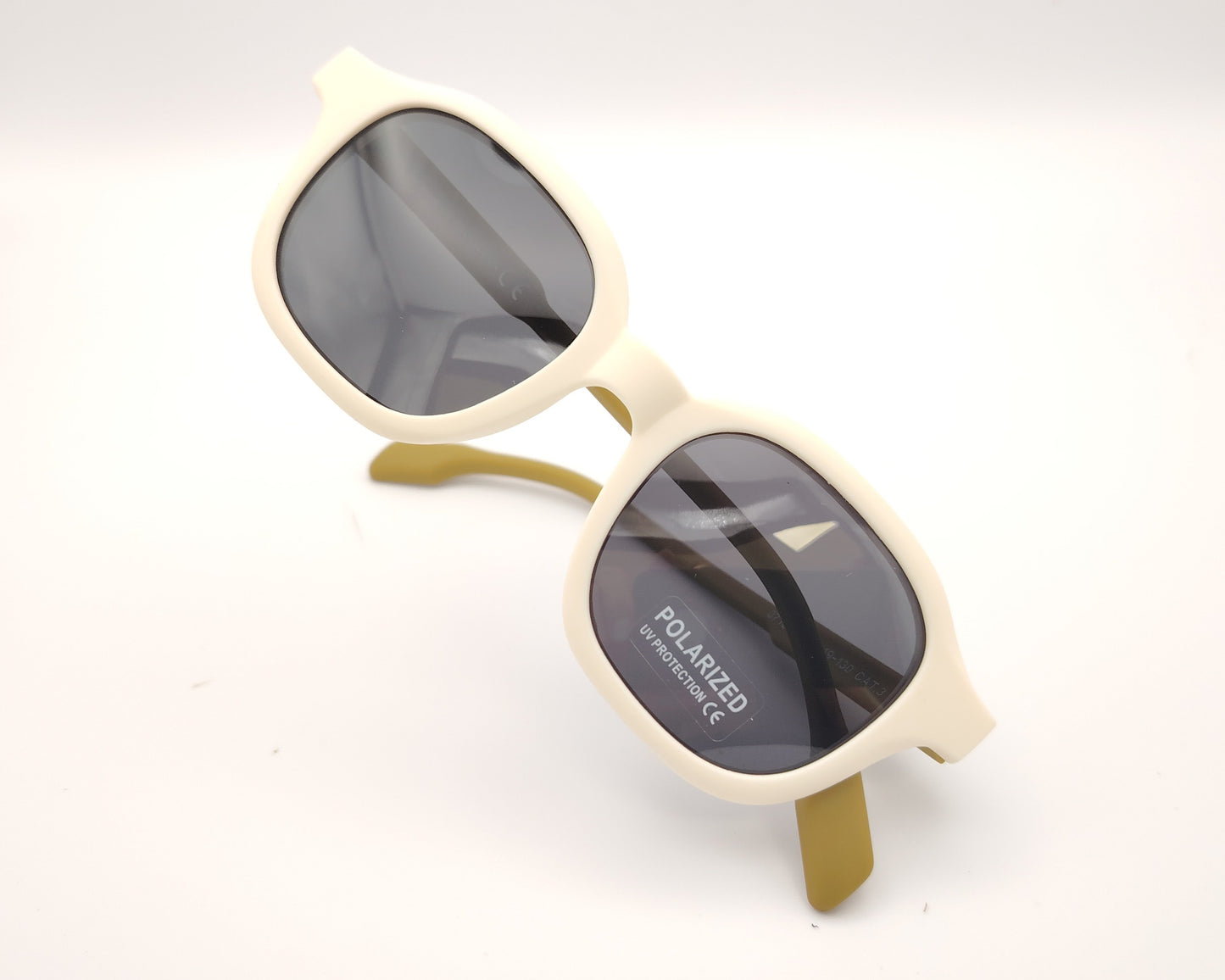 gafas de sol infantiles polarizadas con montura beige y varillas color mostaza con lentes grises.