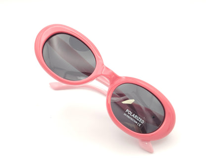 gafas de sol infantiles polarizadas con montura ovalada rosa y varillas en rosa claro y lentes grises con protección uv.