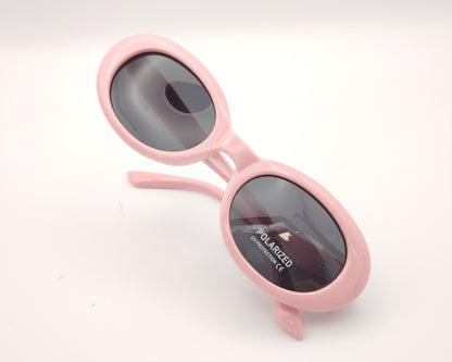 gafas de sol infantiles polarizadas con montura ovalada rosa pastel y lentes grises con protección uv.