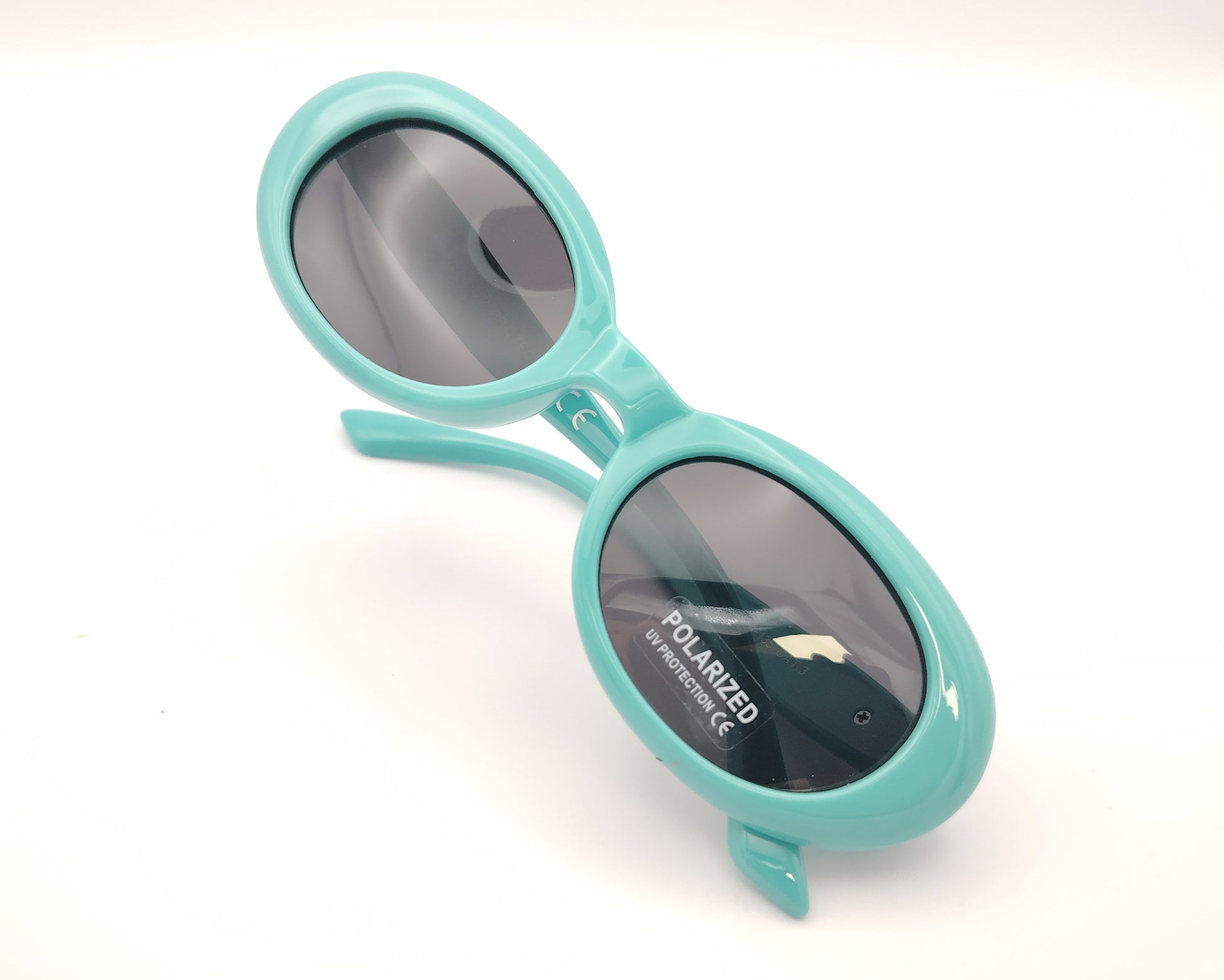 gafas de sol infantiles polarizadas con montura ovalada turquesa y lentes grises con protección uv.