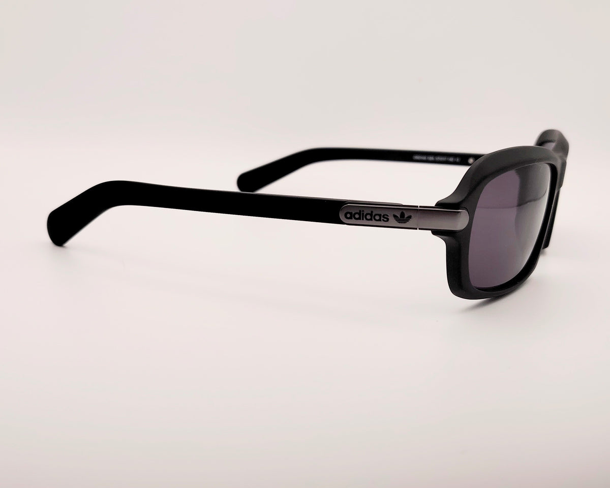 gafas de sol adidas en color negro mate con lentes negras y diseño rectangular ligeramente envolvente