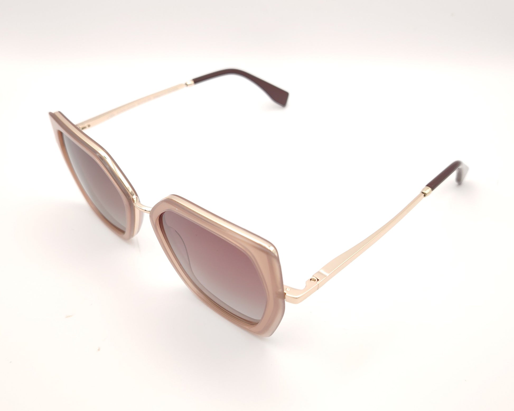 gafas de sol polarizadas rosa translúcido con montura geométrica y varillas doradas