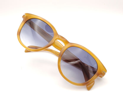 gafas de sol con montura translúcida color miel y lentes degradadas azules de forma redondeada