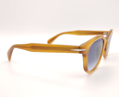 gafas de sol con montura translúcida color miel y lentes degradadas azules de forma redondeada