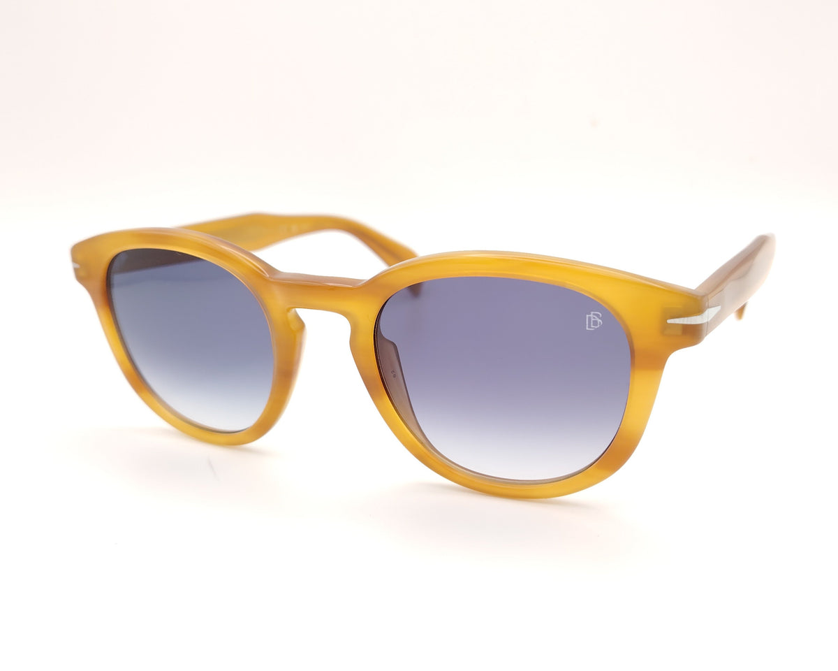 gafas de sol con montura translúcida color miel y lentes degradadas azules de forma redondeada