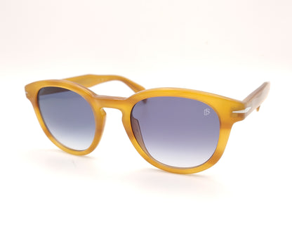 gafas de sol con montura translúcida color miel y lentes degradadas azules de forma redondeada