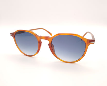 gafas de sol con montura translúcida color ámbar y lentes degradadas azules de forma redondeada
