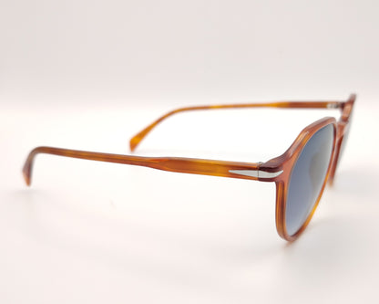 gafas de sol con montura translúcida color ámbar y lentes degradadas azules de forma redondeada