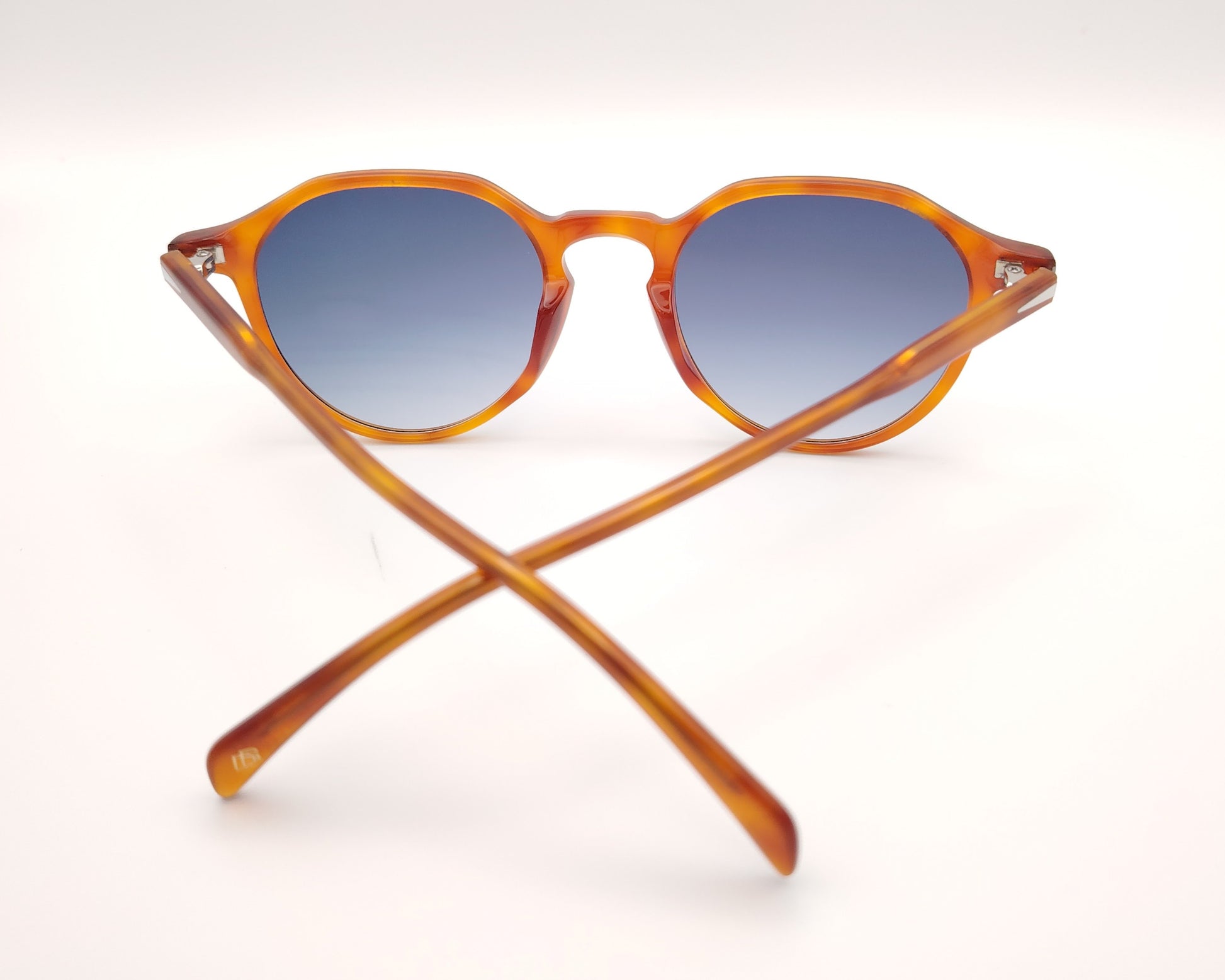 gafas de sol con montura translúcida color ámbar y lentes degradadas azules de forma redondeada