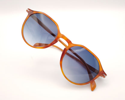 gafas de sol con montura translúcida color ámbar y lentes degradadas azules de forma redondeada
