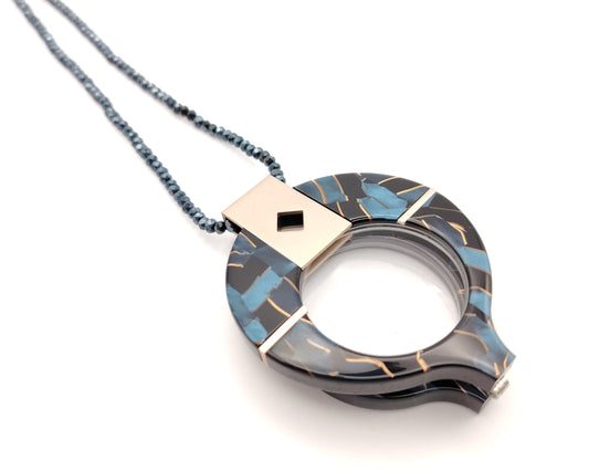 lente de lectura plegable con diseño negro azul y dorado colgado de cadena de cuentas