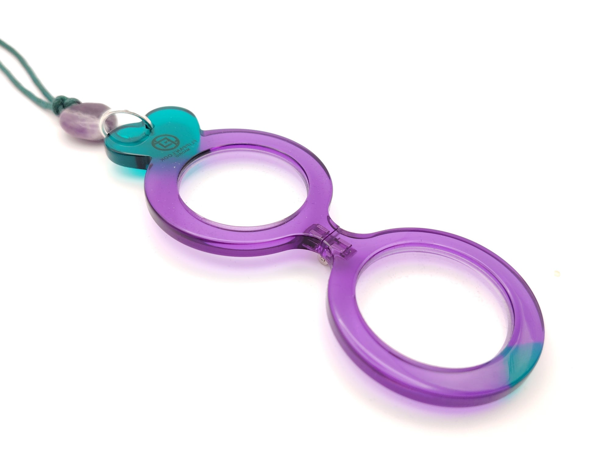 lente de lectura plegable violeta con forma redonda y detalles en turquesa colgado de un cordón