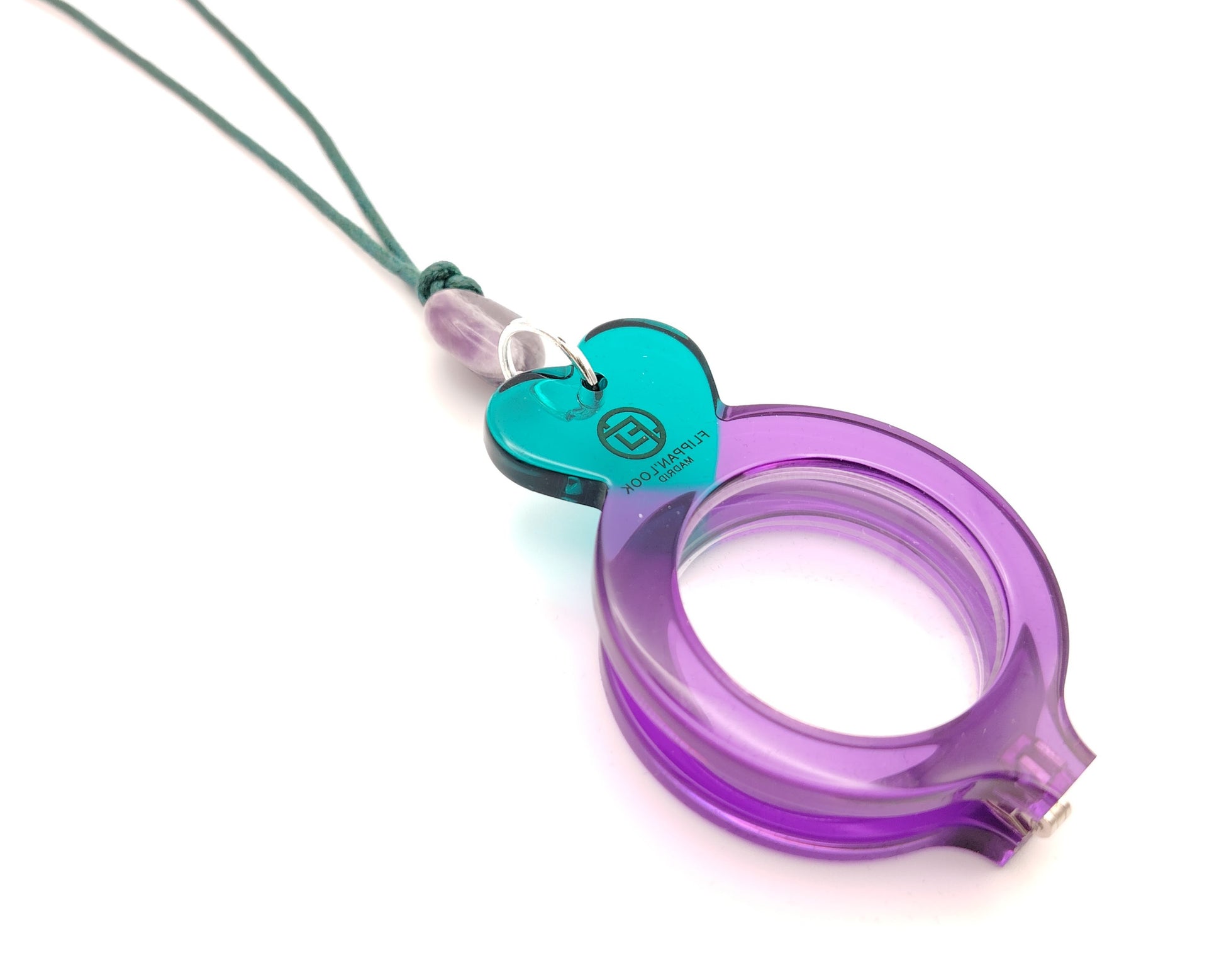 lente de lectura plegable violeta con forma redonda y detalles en turquesa colgado de un cordón