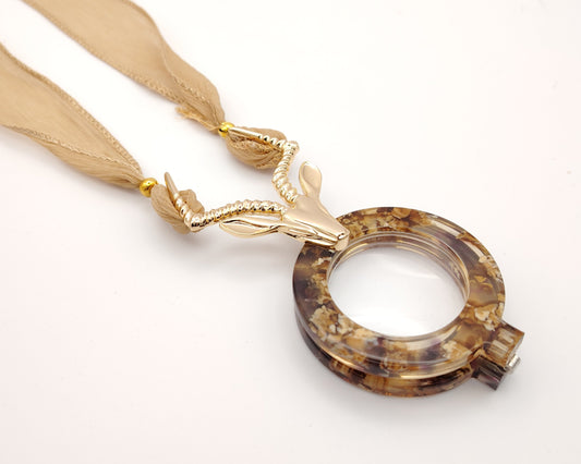 lente de lectura plegable flippan look con diseño jaspeado en tonos tierra y colgante de antílope dorado y cinta para colgar en gasa nude