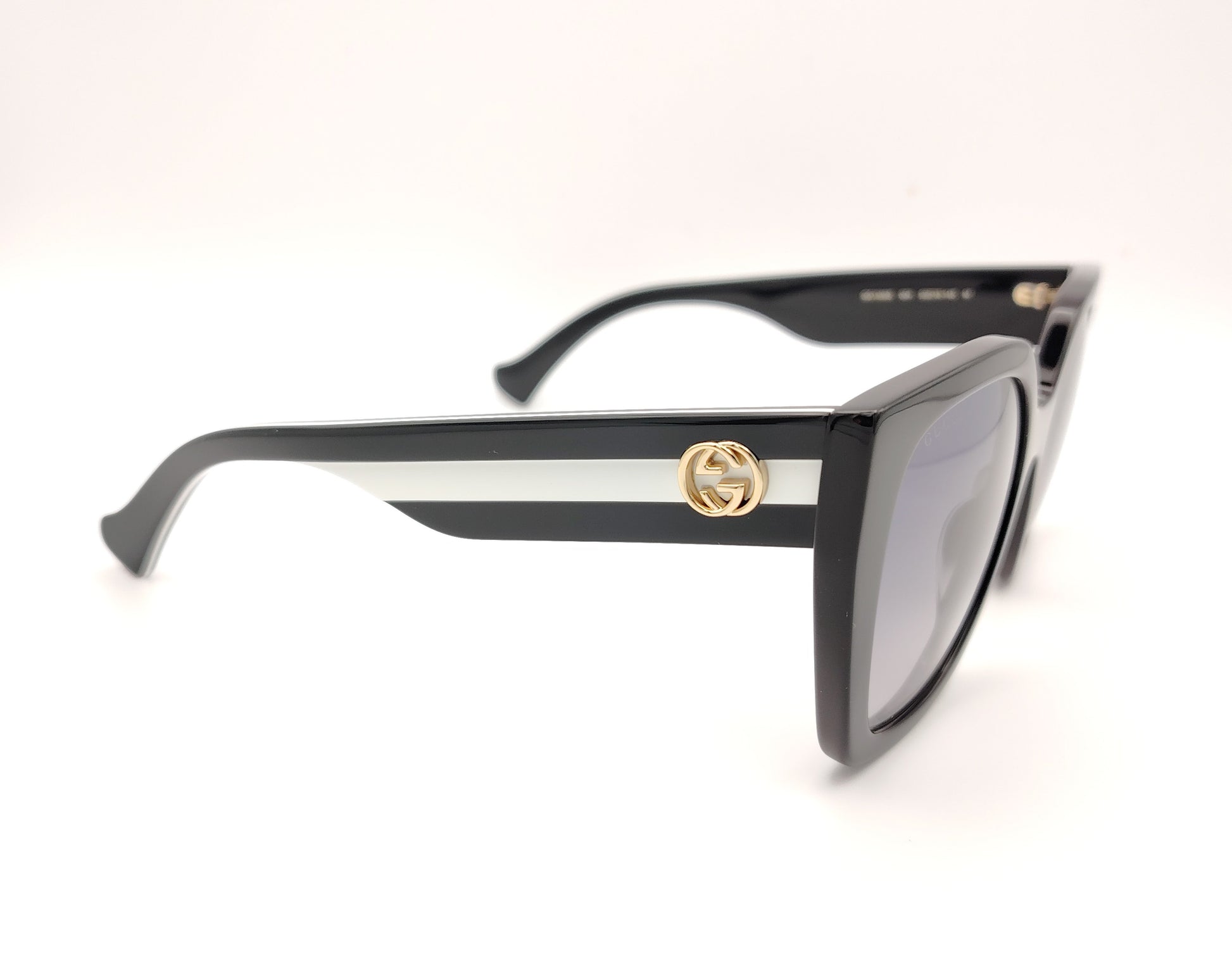 gafas de sol gucci negras oversize y detalle de logo dorado en las patillas bicolor