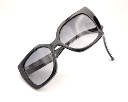 gafas de sol gucci negras oversize y detalle de logo dorado en las patillas bicolor