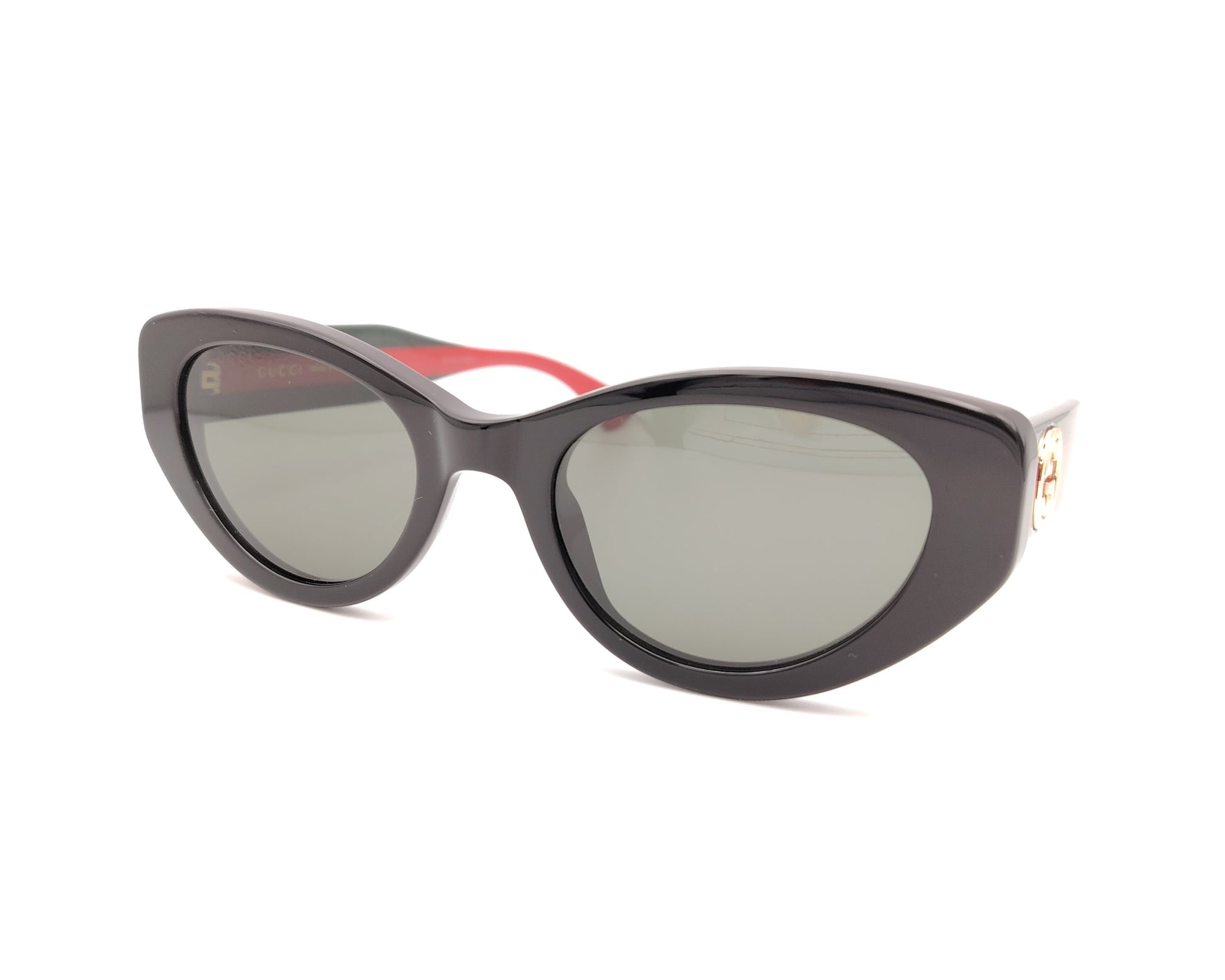 gafas de sol negras estilo cat eye con patillas verdes y rojas y logo dorado

