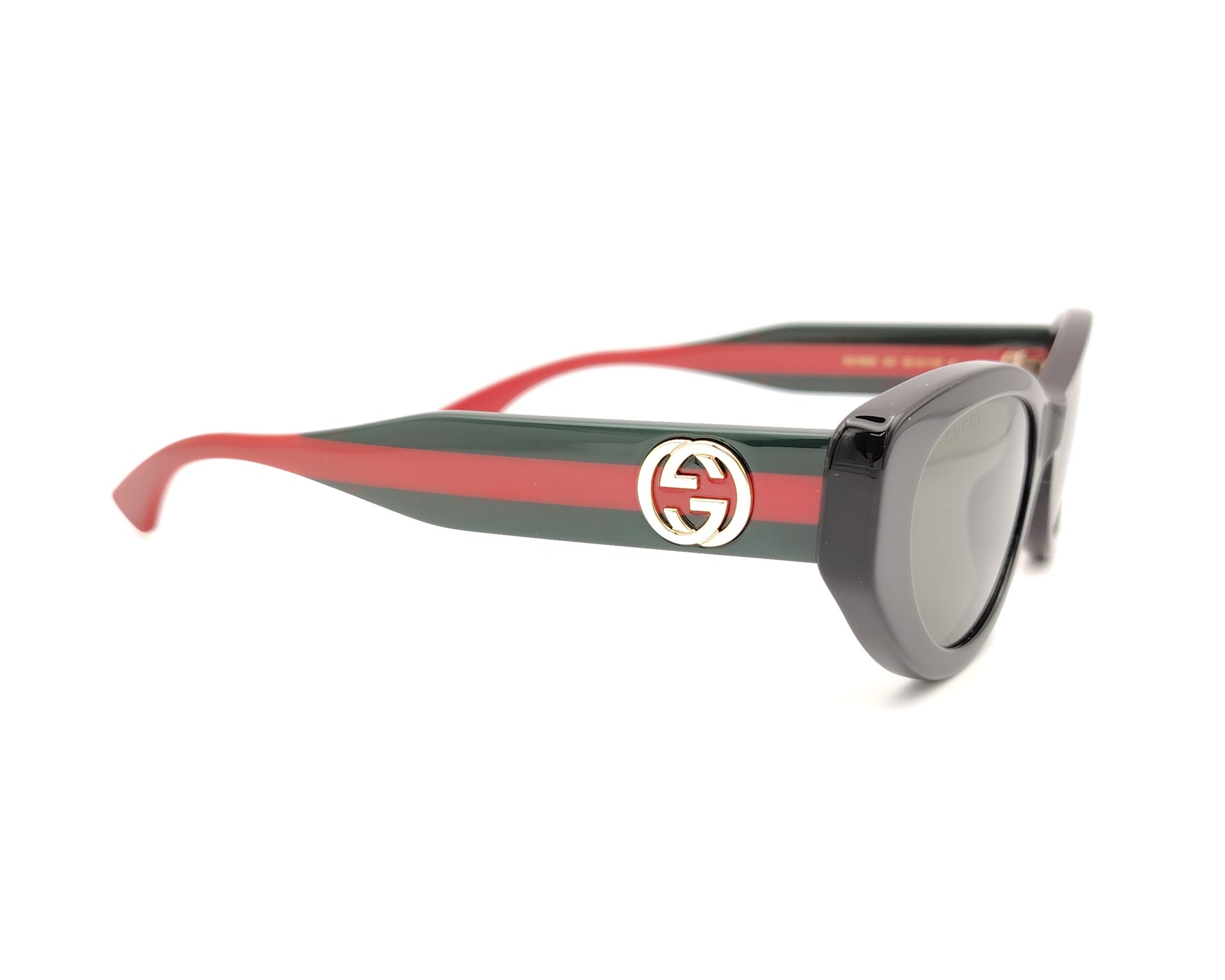 gafas de sol negras estilo cat eye con patillas verdes y rojas y logo dorado

